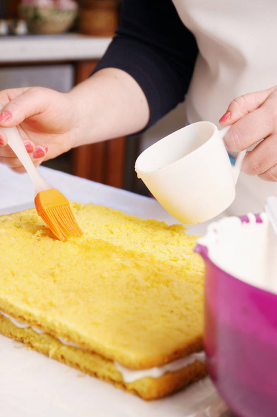 κέικ τον εμποτισμό ροδάκινο σιρόπι με ένα πινέλο - Φωτογραφία, εικόνα