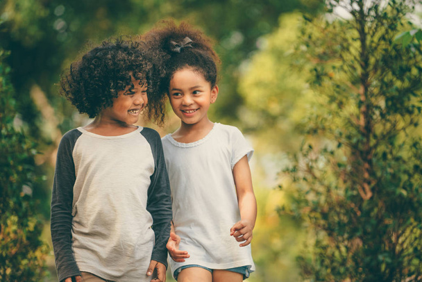 Счастливые мальчик и девочка в парке. Двое афроамериканских детей вместе в саду
. - Фото, изображение