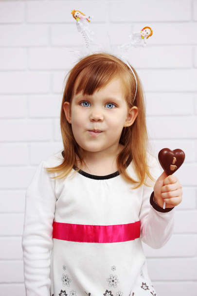 beautiful girl holding a chocolate heart on a stick - Фото, зображення