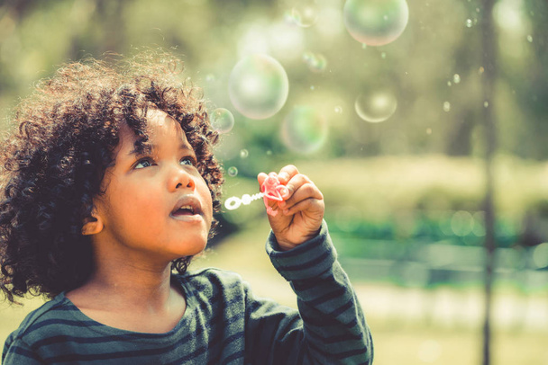 Happy little kid blowing soap bubble in school garden. Child outdoor activity concept. - Photo, Image