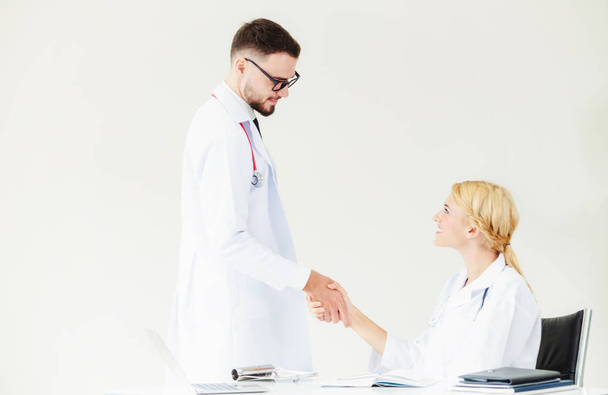 Doctor at the hospital giving handshake to another doctor showing success and teamwork of professional healthcare staff. - Photo, Image