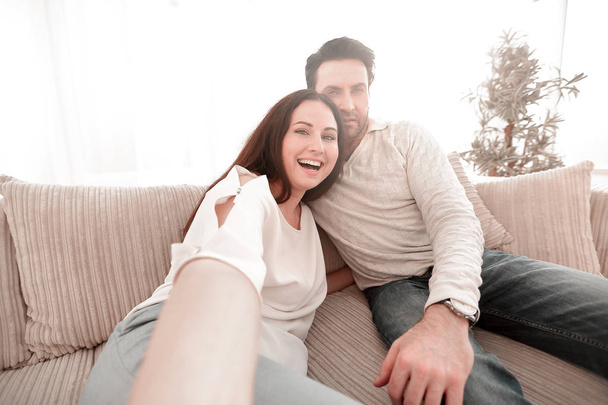 happy couple sitting on the couch in the living room - Фото, изображение