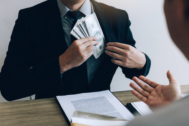 Businessman putting stack of money bills in his suit coat pocket. - Фото, зображення