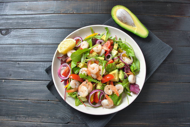Avocado salad with shrimps, cherry tomatoes, arugula beet leaves, red onion, yellow sweet pepper. Healthy lunch plate with vegetables and shrimps  - Fotoğraf, Görsel