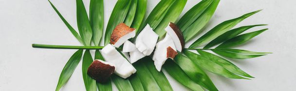 Close view of white coconut pieces on palm leaf over white stone background - Foto, imagen