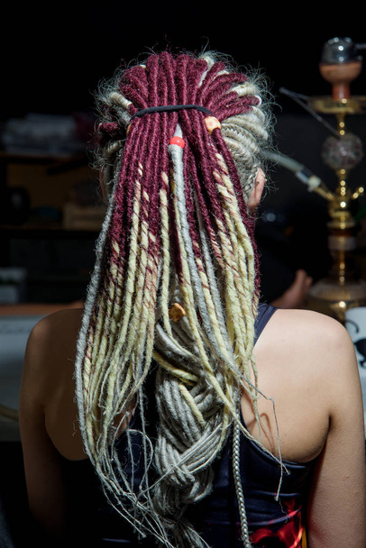 Light colored dreadlocks on the hair. Hair accessories. Dreadlocks braided in pigtails. Pierced ear. Girl. Wooden beads on dreadlocks. Dred texture. - Фото, зображення