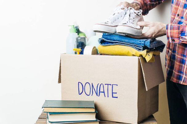 Kleding doneren en voedsel donatie Concept. Een man met een donatie box met kleding, schoenen en hygiëneproducten. Kopiëren van ruimte - Foto, afbeelding