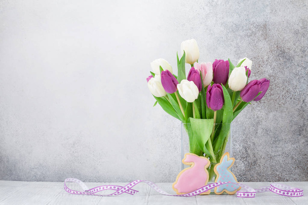 Pasen-wenskaart met tulp bloemen boeket en konijn cookies. Met ruimte voor uw groeten - Foto, afbeelding