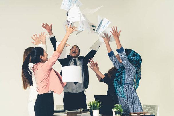 Smiling business people having fun by throwing papers in the air celebrating business success in the modern office. Happy workplace and casual career company concept. - Фото, изображение