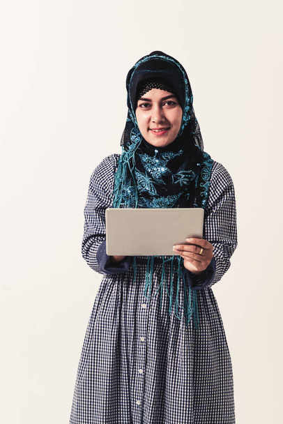 Portret arabski Muzułmanin kobiety w kolorowe ubrania tradycyjnych przy użyciu komputera przenośnego na białym tle. - Zdjęcie, obraz