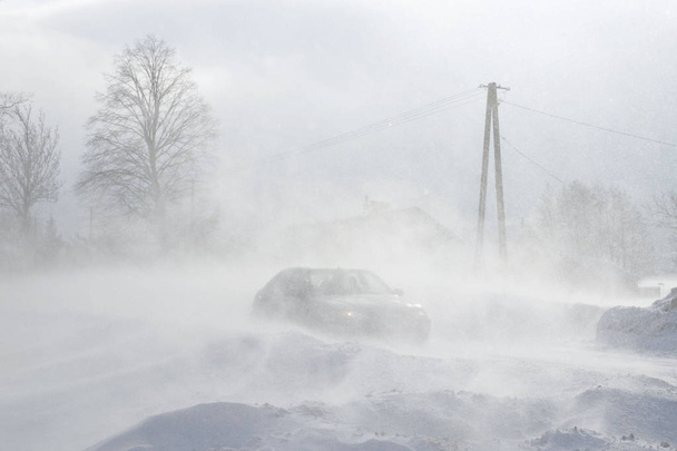 Автомобиль пробирается через дрейфы по опасной дороге, покрытой снегом. Частный транспорт борется с зимними стихиями. Трудности в движении во время снежной бури. Последствия холодной погоды
. - Фото, изображение
