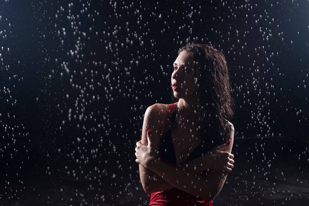 Muotokuva nuori aistillinen nainen hoikka punainen mekko poseeraa alle vesipisaroita
 - Valokuva, kuva