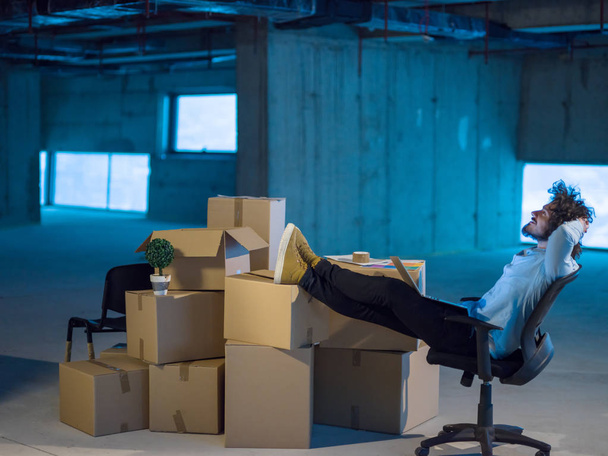молодий чоловік архітектор на будівельному майданчику перевіряє документи та бізнес робочий процес за допомогою ноутбука з картонними коробками навколо нього в новому стартовому офісі
 - Фото, зображення