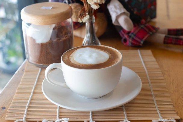 warme koffie in de cup en koffieboon op de houten tafel - Foto, afbeelding