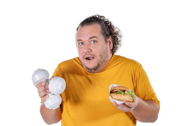 Funny fat man eating unhealthy food and trying to take exercise isolated - Фото, зображення