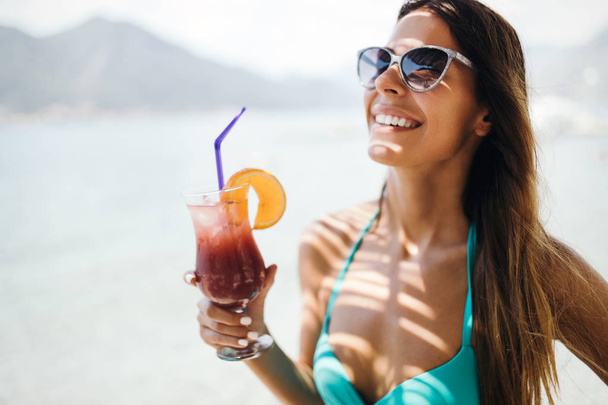 Beautiful woman drinking cocktails during summer vacation on beach - Valokuva, kuva