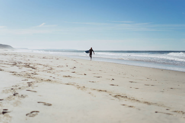 az ember a surf fórumon az óceán partján. A nedves ruha a szörfös. Nazare, Portugália. - Fotó, kép