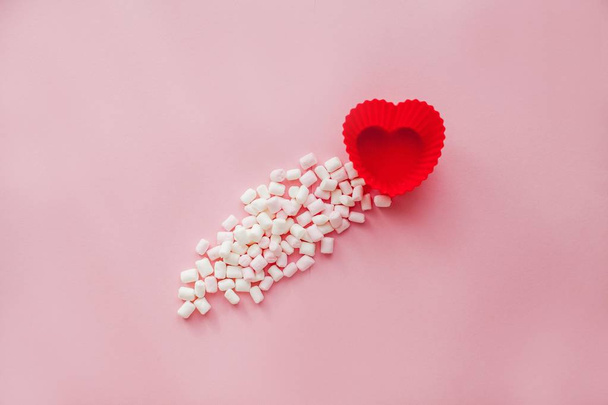 Red heart shape with marshmallows on pink background. Valentine's Day. Love. - Foto, afbeelding