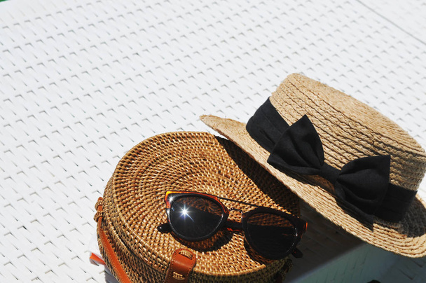 Round straw bag and straw hat with black sunglasses on white background - Valokuva, kuva