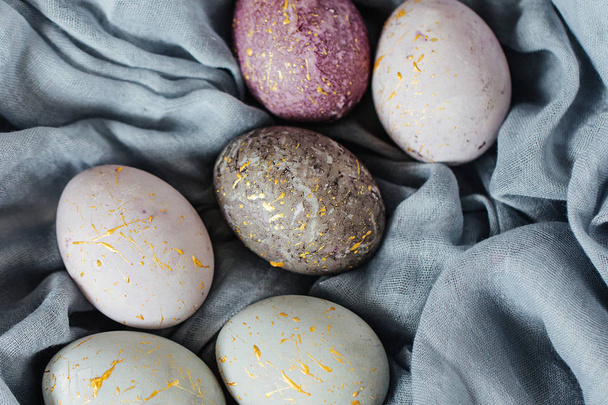 Stylish gray, violet and blue Easter eggs on color textile  - Фото, изображение