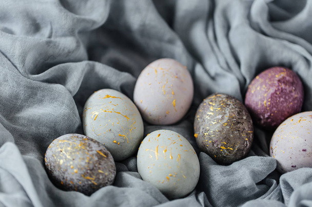 Stylish gray, violet and blue Easter eggs on color textile  - Foto, Bild