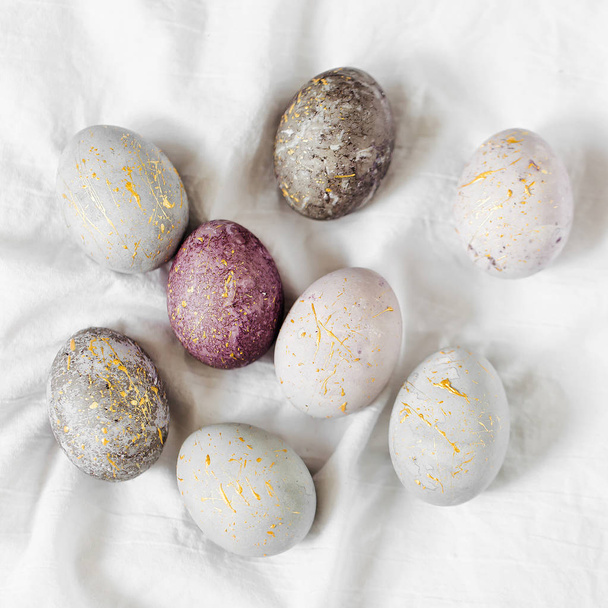 Stylish gray, violet and blue Easter eggs on color textile  - Фото, изображение