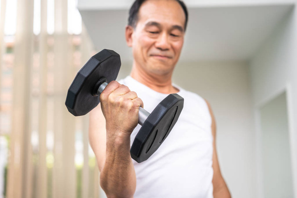 Senior man lifting dumbbell in fitness gym. Senior healthy lifestyle. - Photo, Image