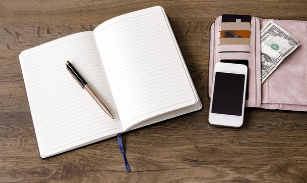ordinateur portable avec stylo, portefeuille avec argent et cartes de réduction, téléphone, sur fond en bois
 - Photo, image