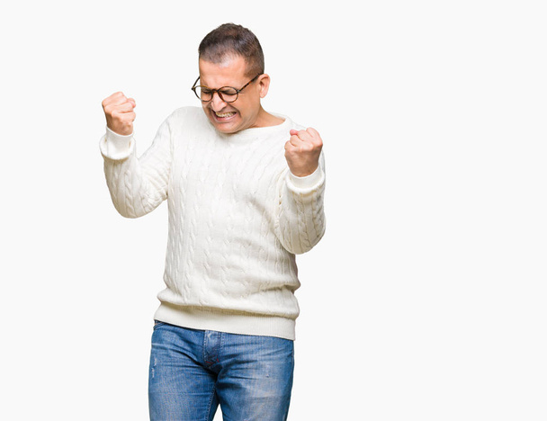 Араб средних лет в очках на изолированном фоне очень счастлив и взволнован, делая жест победителя с поднятыми руками, улыбаясь и крича об успехе. Концепция празднования
. - Фото, изображение