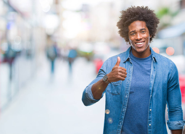 Afro american man over isolated background doing happy thumbs up gesture with hand. Approving expression looking at the camera with showing success. - Photo, Image