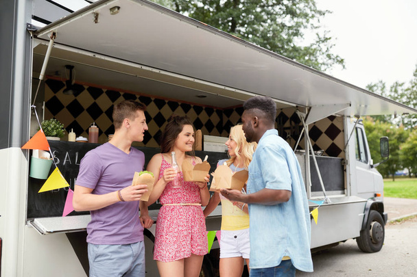 happy friends with drinks eating at food truck - Foto, Imagen