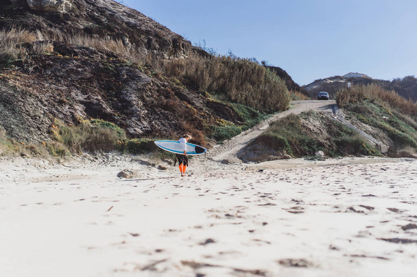 surf girl on the ocean coast in a wet suit with surf board, Nazar, Portugal. - Foto, Imagem