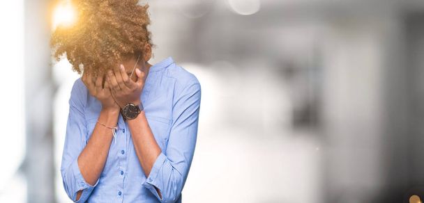 Mooie jonge Afro-Amerikaanse zakenvrouw over geïsoleerde achtergrond met trieste uitdrukking waarin gezicht met handen terwijl het huilen. Depressie concept. - Foto, afbeelding