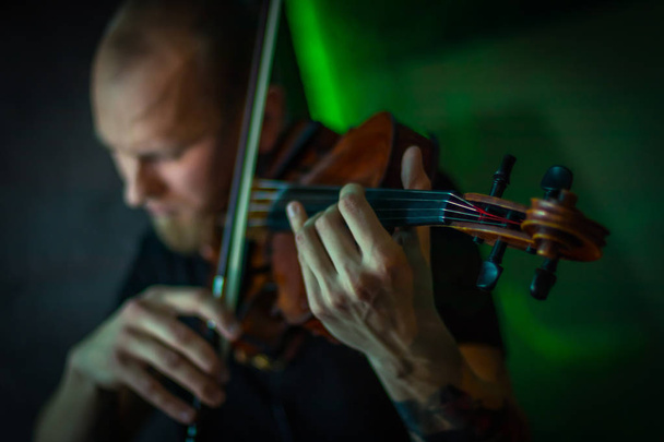 De violist speelt de viool. Brutale man met een baard spelen van de viool fatale simony. Close-up - Foto, afbeelding
