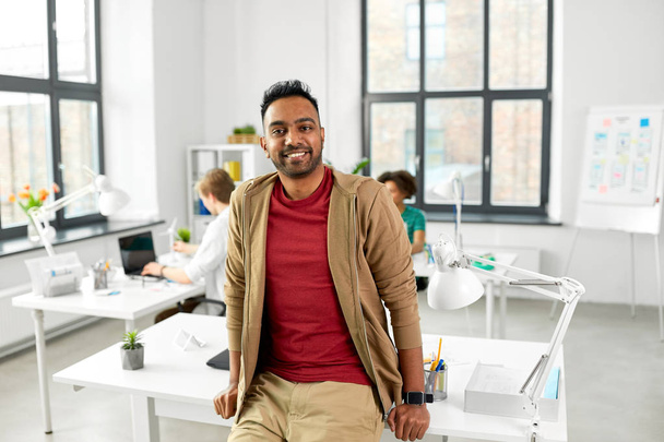 smiling indian man with smart watch at office - Foto, Bild