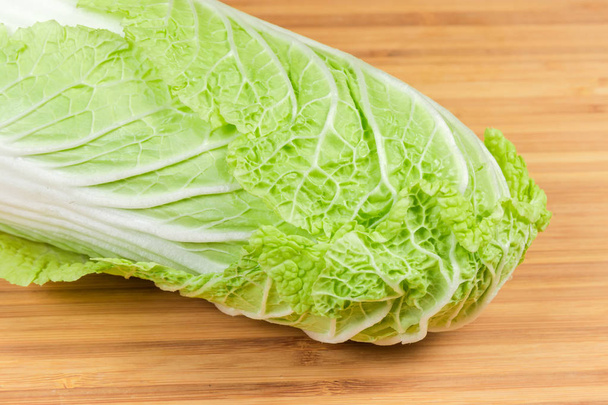 Upper part of head napa cabbage also known as chinese cabbage on the bamboo wooden cutting close-u - Foto, Imagen
