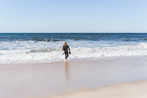 серфер с ластами и кузовом в гидрокостюме на берегу океана
 - Фото, изображение