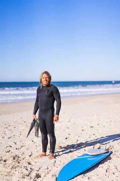 surfer with flippers and a bodyboard in a hydro suit on the ocean shore - Foto, Bild