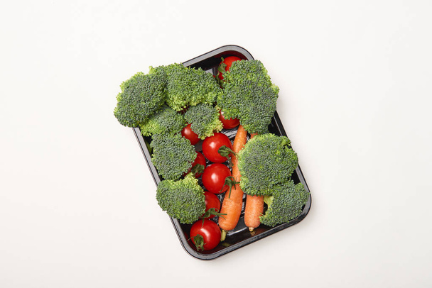 Top view of organic vegetables in black bowl on white background - Φωτογραφία, εικόνα