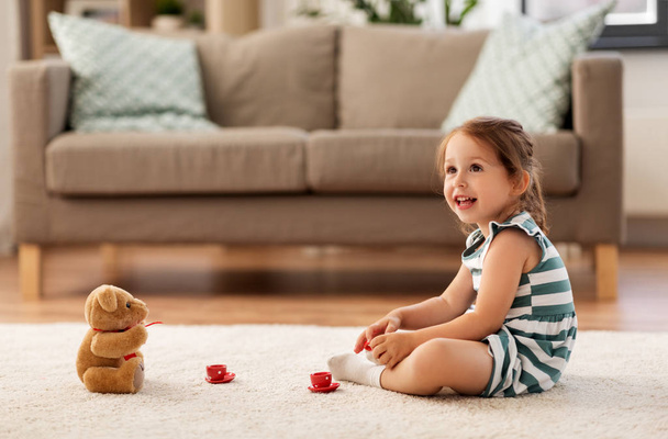 Девочка играет с игрушечным чайным сервизом дома
 - Фото, изображение