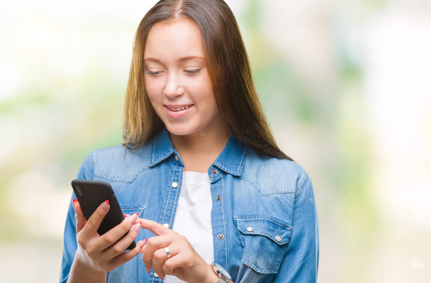 Jonge mooie Kaukasische vrouw SMS verzenden bericht via smartphone over geïsoleerde achtergrond met een blij gezicht permanent en lachend met een vertrouwen glimlach weergeven tanden - Foto, afbeelding