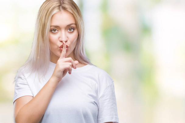 Jeune femme blonde sur fond isolé demandant à être calme avec le doigt sur les lèvres. Silence et concept secret
. - Photo, image