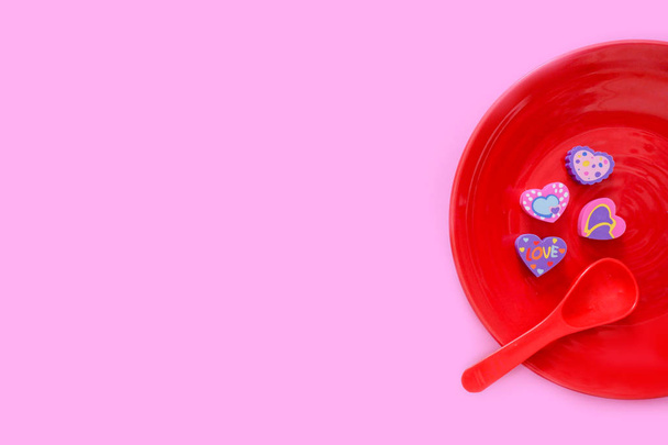Valentine is Day Colorful Heart on a Red Plate and Spoon for Love Concept. Flat Eraser in Shape of a Heart with Romantic. Different Rubber Heart Symbol Isolated on Pastel Pink Paper Background. - Foto, Imagem