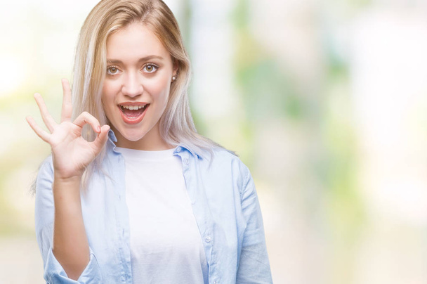 Jeune femme blonde sur fond isolé souriant positif faire ok signe avec la main et les doigts. Expression réussie
. - Photo, image