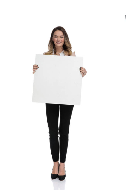 jeune femme d'affaires debout sur fond blanc et tenant signe vide, image pleine longueur
 - Photo, image