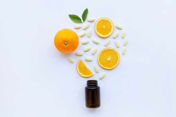 Vitamin C bottle and pills with orange fruit on white background. - Foto, afbeelding
