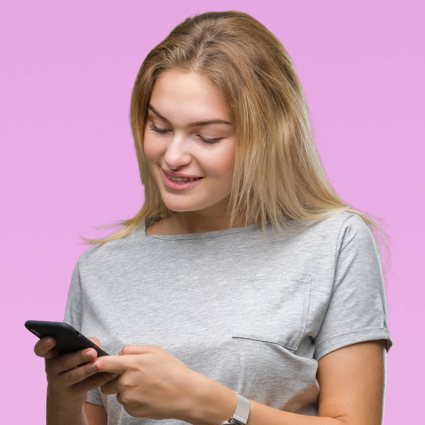 Mulher branca jovem enviando mensagem usando smartphone sobre fundo isolado com um rosto feliz de pé e sorrindo com um sorriso confiante mostrando dentes
 - Foto, Imagem
