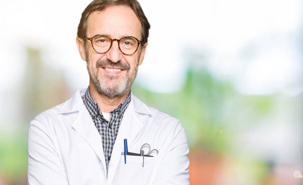 Middelbare leeftijd arts mannen dragen medische jas blij gezicht lachend met gekruiste armen kijken naar de camera. Positief persoon. - Foto, afbeelding