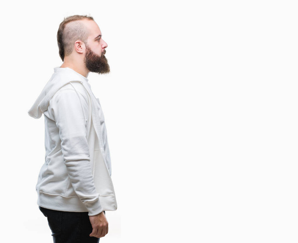 junge kaukasische Hipster-Mann trägt Sportkleidung über isoliertem Hintergrund Blick zur Seite, entspannen Profil Pose mit natürlichem Gesicht mit selbstbewusstem Lächeln. - Foto, Bild