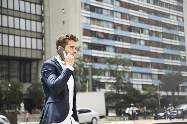 Good looking guy on smart phone in city - Photo, Image